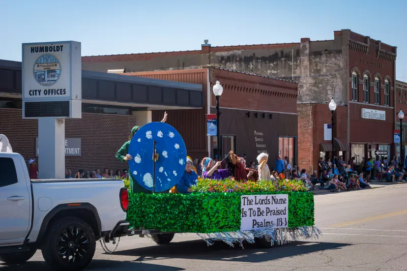 A float with a giant clock face and a sign reading The Lord's Name Is To Be Praised, Psalm 113:3.