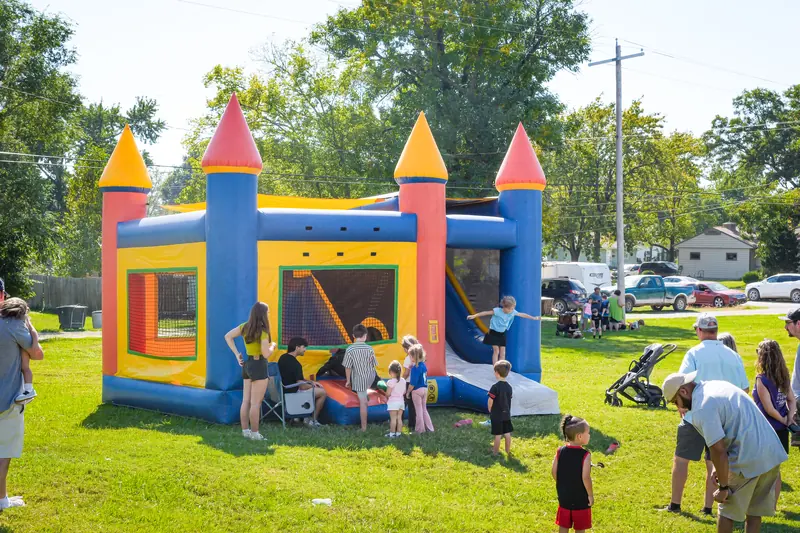Children line up at a castle bounce house on the square's lawn.